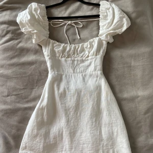 Vit kortklänning med puffärmar med snörning från Zara - Superfin vit klänning från Zara med puffiga kortärmar och knytning i ryggen. Perfekt för student eller konfirmation!! Aldrig använd💕 köptes för student men har köpt en annan klänning 