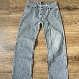 Grå jeansbyxor från Montén - Säljer ett par klassiska grå jeansbyxor från Montén med raka ben och femficksdesign. Byxorna har normal passform, ny pris 1200