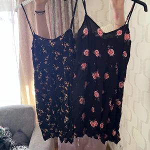 Två blommiga sommarklänningar med smala axelband - Säljer två söta blommiga klänningar med smala axelband. Den ena är svart med små gula blommor och den andra är svart med rosa rosor. Perfekta för varma dagar och enkel att styla med sneakers eller sandaler.
