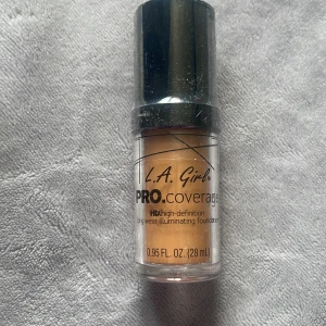 L.A. Girl PRO.coverage foundation - Ljusbeige foundation från L.A. Girl i PRO.coverage-serien. Kommer i en genomskinlig plastflaska med svart pump och lock. Ger en illuminating finish och är high-definition longwear. tan 