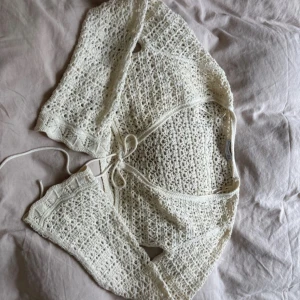 Vit virkad kofta från Stradivarius - Säljer en superfin vit virkad kofta från Stradivarius i storlek M. Koftan är croppad med knyt framtill och har lång ärm. Perfekt att slänga över ett linne eller klänning för en söt och trendig look.