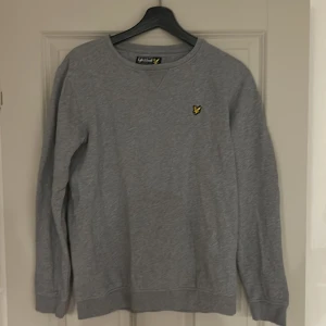 Grå tröja från Lyle & Scott - Säljer en stilren grå tröja från Lyle & Scott med deras ikoniska logga på bröstet. Tröjan har långa ärmar och rund halsringning, perfekt för en avslappnad look. Passar bra till både jeans och chinos. Pris kan diskuteras via meddelanden!