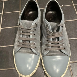 Grå sneakers från Lanvin - Jag säljer nu mina snygga grå sneakers från Lanvin med en stilren design. Skorna har en captoe i bra skick och snörning framtill. Skorna är i ett väldigt bra skick utan några större skador. Skorna är storlek 46 men små i storleken, så 45 funkar toppen dessutom.Priset kan även diskuteras vid en snabb affär, och för minsta lilla fundering/fråga så är det bara att kontakta mig.🙌🏼