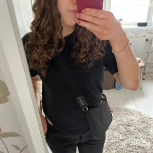 Svart axelväska från DAY ET - Snygg och praktisk svart axelväska från DAY ET. Väskan har en justerbar axelrem och stängs med dragkedja. Har flera små fack inuti. Ge gärna prisförslag🩷