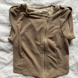 Topp/väst - Så cool beige väst från Zara med korta ärmar och en asymmetrisk dragkedja framtill. Går både att ha som topp eller öppen väst💗💗