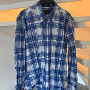 Blå och vit rutig skjorta från GANT storlek S - Säljer min brorsas blå och vit rutig skjorta från GANT i storlek S. Skjortan har långa ärmar och knappar framtill. Passade han när han var runt 168 cm. Skjortan är i bra skick.