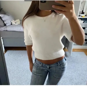 Vit stickad tröja - Säljer en stilren vit stickad tröja med korta ärmar. Perfekt för en avslappnad look. Tröjan har en croppad passform som ger en modern touch. Passar bra till jeans eller kjol.