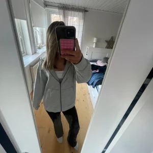 Grå hoodie med dragkedja - Säljer en bekväm grå hoodie med dragkedja och långa ärmar. Perfekt för en avslappnad stil. Den har en klassisk design med fickor framtill.