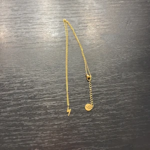 Guldhalsband med blixt  - Snyggt guldhalsband med en blixtberlock. Perfekt för den som älskar stil. Kedjan är tunn och elegant, vilket gör den lätt att bära till olika tillfällen.