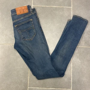Blå jeans från tiger of Sweden  - Snygga blå jeans från Diesel med klassisk femficksdesign och knappgylf. Jeansen har en normal passform och är perfekta för en avslappnad stil. Märkeslappen i läder baktill ger en extra touch av stil. Skick 9,5/10