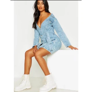 Blå jeansklänning med bälte/ helt ny utan prislapp - Snygg blå jeansklänning med v-ringning och bälte i midjan. Klänningen har långa ärmar och en cool tvättad look. Perfekt för en trendig stil.