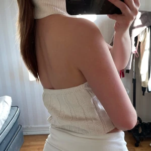 Vit ribbad halterneck topp - Säljer en stilren vit ribbad halterneck topp. Den är ärmlös och har en hög krage som ger en elegant look. Perfekt för både vardag och festliga tillfällen.🪩🎱