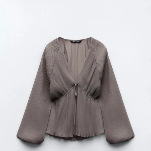 Grå/beige plisserad blus från Zara - Jättefin grå blus från Zara med plisserad design och v-ringning. Blusen har långa ärmar och en knytning framtill. Endast provad då den var för stor för mig <3
