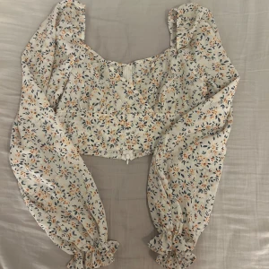 Blommig blus med puffärmar - Blommig blus med puffiga långa ärmar samt dragkedja baktill