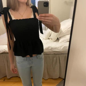 Svart topp med volangdetaljer - Snygg svart topp med volangdetaljer och knytband på axlarna🥰