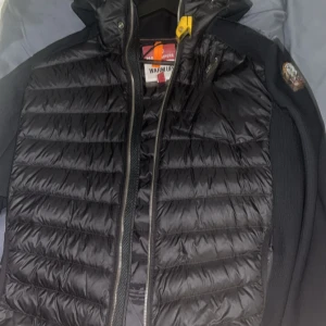 Svart pufferjacka med huva från Parajumpers - Snygg svart pufferjacka med huva och dragkedja framtill från parajumpers. Jackan har långa ärmar och en quiltad design. Perfekt för kyligare dagar. Använd men fortfarande bra skick. Pris kan diskuteras. Står ej för frakten, kan mötas upp i GBG