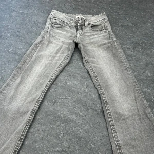 Grå jeans från Gina Tricot - Snygga grå jeans från Gina Tricot i en klassisk femficksmodell. De har en normal passform och är perfekta för en avslappnad stil. Jeansen har en dragkedja och knapp framtill.