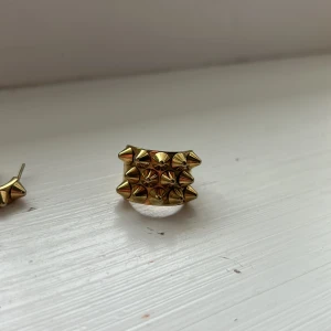 Guldörhängen med nitar och likadan ring 💛 - Snygga guldörhängen med nitar i en unik design. Perfekta för att ge en edgy touch till din stil. De är runda och har en cool, modern känsla. Storlek på ringen är 18.80 💛