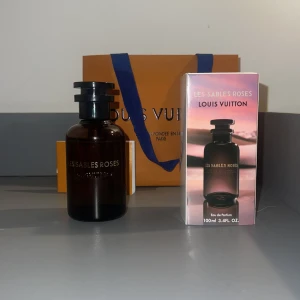 Les Sables Roses parfym från Louis Vuitton - Exklusiv parfym Les Sables Roses från Louis Vuitton i en elegant mörk glasflaska. Förpackningen är stilren med en rosa och svart design. Flaskan rymmer 100 ml och kommer med originalförpackning och påse. Perfekt för den som söker en lyxig doftupplevelse.