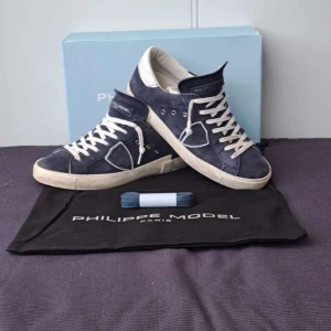 Blå sneakers från Philippe Model - Snygga blå sneakers från Philippe Model med vita snören och en vit sula. Perfekta för en stilren look.