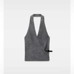 Grå omlott topp med knäppdetalj - Snygg grå omlott topp med djup v-ringning och knäppdetalj i sidan. Perfekt för en stilren look.