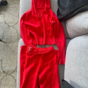 Rött Destiny set - Snyggt rött  Destiny set med dragkedja och matchande byxor. Hoodien har långa ärmar och ribbade detaljer. Perfekt för en avslappnad stil. Nypris 1200:- 