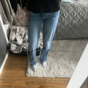 Blå jeans - Säljer ett par klassiska blå jeans med normal passform. De har en rak stil och är perfekta för en avslappnad look. Jeansen har en traditionell femficksdesign och är tillverkade i ett slitstarkt denimtyg.