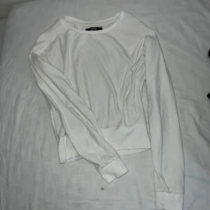 Vit tröja från BikBok - Säljer en stilren vit tröja från BikBok i storlek S. Tröjan har långa ärmar och en rund halsringning. Den är tillverkad i ett mjukt material och har ribbade muddar vid ärmslut och nederkant. 
