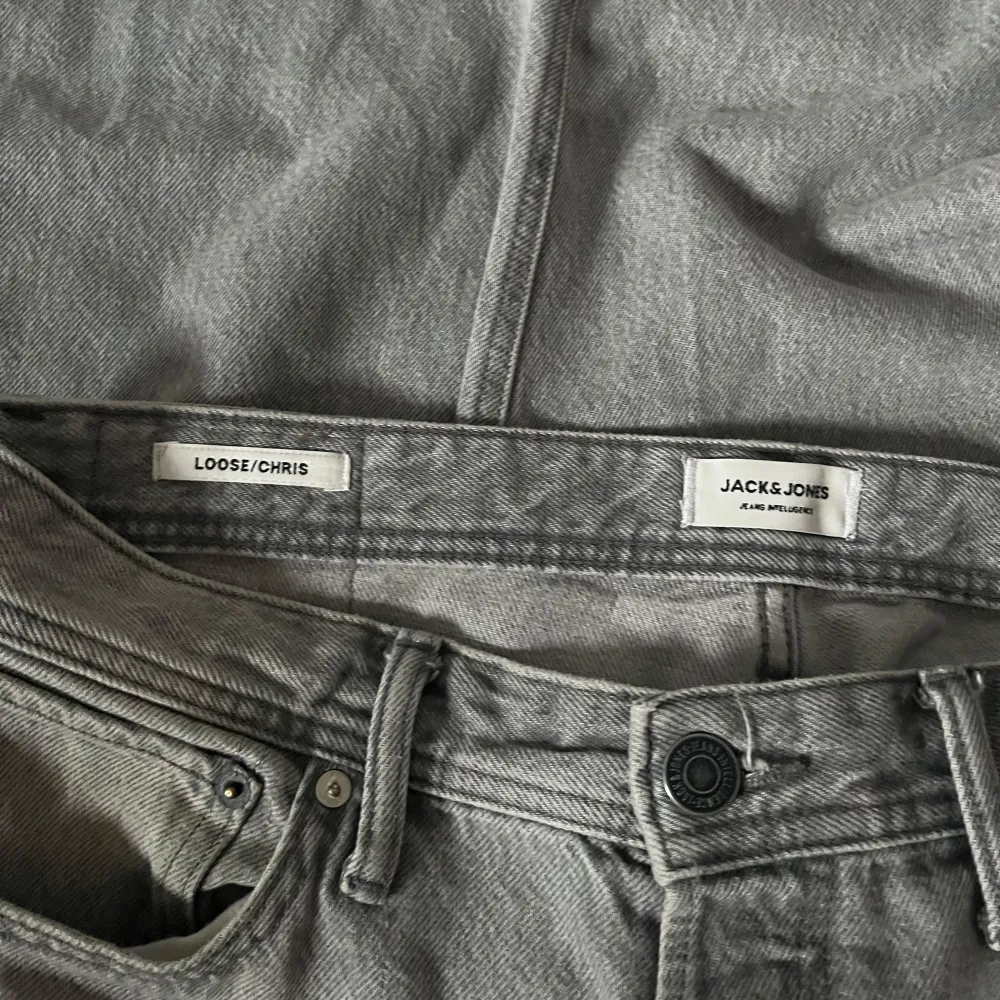 Säljer ett par grå jeans från Jack & Jones i modellen Loose/Chris. De har en regular passform och klassisk femficksdesign med knappgylf. Perfekta för en avslappnad stil. Storlek 32/30. Farkut & Housut.