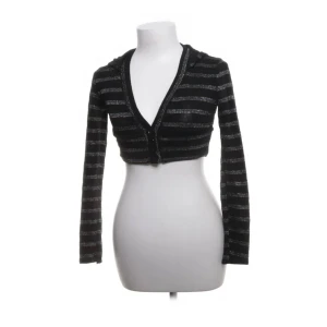 Svart randig cropped kofta - Snygg svart kofta med  ränder i blått och guld. Den är croppad och har en djup v-ringning med 4 knappar. Ser ut att vara i storlek xs/s