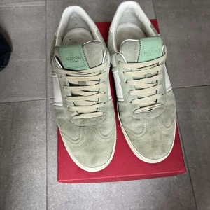 Valentino flycrew - Snygga Valentino sneakers i en fräsch grön och vit färgkombination. Skorna har en stilren design med snörning och är tillverkade i mocka och skinn. Pris kan diskuteras. 7 nitar saknas!