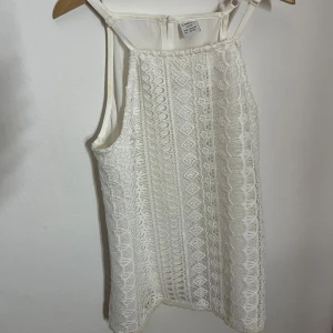 Vit spetslinne från Lindex. - Säljer ett sött vitt spetslinne från Lindex i storlek 146/152. Linnet har ett vackert spetsmönster och justerbara axelband. Perfekt för varma sommardagar eller som ett lager under en kofta. Skriv bara vid frågor.