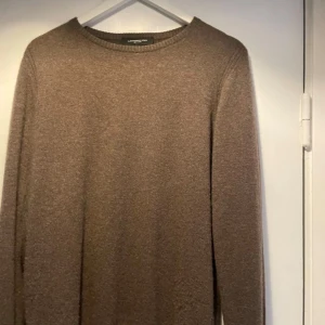 100% Kashmir tröja - Säljer en stilren brun tröja. Tröjan är långärmad och har en klassisk rund halsringning. Perfekt för både vardag och mer uppklädda tillfällen. Hör av er om ni har frågor:)