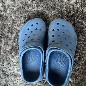 Blå sandaler - Säljer ett par bekväma blå sandaler med hålmönster och justerbar rem. Perfekta för sommarens alla äventyr.