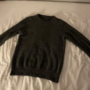 Mörkgrå tröja - Säljer en stilren mörkgrå tröja med rund halsringning. Tröjan har långa ärmar och ribbade kanter vid ärmslut och nederkant. Perfekt för kyligare sommar dagar. Nypris 600. merino/kashmir 