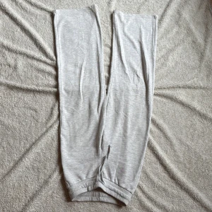 Grå mjukisbyxor från Gina Tricot - Säljer ett par bekväma grå mjukisbyxor från Gina Tricot. Byxorna har en elastisk midja med snörning för justerbar passform. Perfekta för en avslappnad stil.