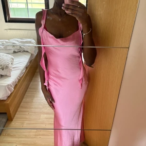 Rosa långklänning med volangdetaljer - Rosa siden långklänning med volangdetaljer längs axelbanden. Klänningen har en smickrande passform och är perfekt till balen / andra fester , den är slutsåld från Gina Tricot (Nypris 599) passar både xs-s
