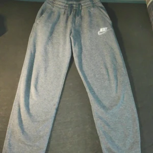 Grå mjukisbyxor från Nike - pris kan diskuteras!! Säljer ett par grå mjukisbyxor från Nike med elastisk midja och snörning. Byxorna har en avslappnad passform. säljer pga att den inte passar mer