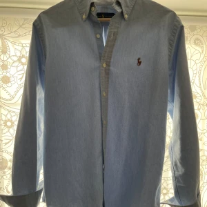 Ralph Lauren Skjorta - Säljer denna ljusblåa skjorta i storlek S men sitter mer som M. Skjortan är i bra skick skulle säga 8,5/10. 
