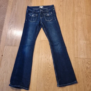 Blå bootcut jeans - Snygga blå bootcut jeans med dekorativa fickor och knappar. Storlek 152, aldrig använda.