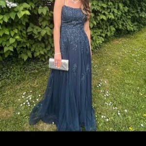 Mörkblå Balklänning  - Elegant mörkblå balklänning från JJ's House med vackra spetsdetaljer och smala axelband. Perfekt för en formell tillställning. Klänningen har en flytande kjol och en figursydd överdel som ger en smickrande silhuett. Har några märkningar men inget stort så skriv får fler närmare bilder🩷Köpt för 2271 och andvänd en gång så är i bra skick där av detta pris! Men buds gärna ändå!😊