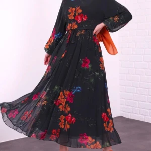 Olive blommig långklänning - Ej använd. Säljer en elegant olive långklänning med färgglada blommor i rött, orange och blått. Klänningen har långa ärmar och ett knytband i midjan för en smickrande passform. Perfekt för en stilfull look.