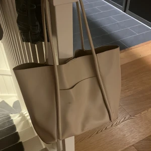 Beige axelväska från Scorett  - Snygg och rymlig beige axelväska med ett extra fack framtill. Väskan har några små märken men syns knappt om man inte kolla noga. På bild nummer 5 är de ett fack man kan lägga i väskan om men inte vill ha de stora utrymmet. Skriv om du har funderingar eller vill få fler bilder🩷🩷