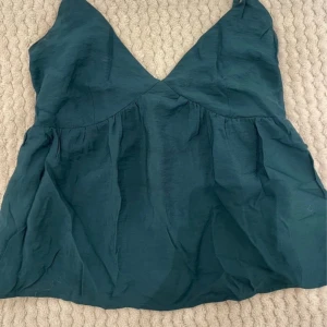 Mörkgrön ärmlös topp - Säljer en stilren mörkgrön ärmlös topp.