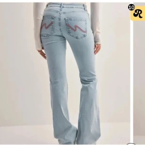 Ljusblå bootcut jeans med slitningar - Snygga ljusblå bootcut jeans med slitningar på knäna och broderade detaljer på bakfickorna. Perfekta för en avslappnad stil med en touch av edge.