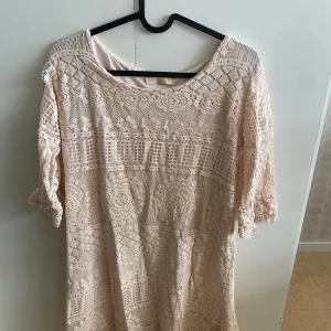 Beige spetsklänning från chica london - Säljer en vacker beige spetsklänning från chica london. Klänningen har ett intrikat mönster och trekvartsärmar. Perfekt för en somrig look med sin ljusa ton och luftiga design.