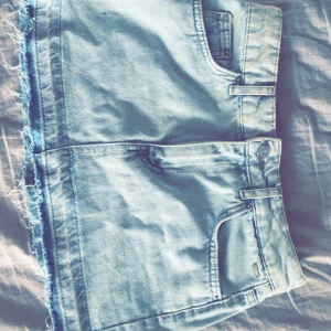 Ljusblå jeanskjol från Pull&Bear - Snygg ljusblå jeanskjol från Pull&Bear med rå kant och klassiska femficksdetaljer. Perfekt för en avslappnad stil. Tillverkad i Turkiet.