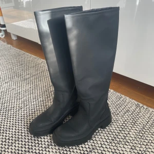 Svarta höga stövlar - Säljer ett par svarta/mörkgrå stövlar från Zara. Slutar precis innan knäna på mig. Grövre sula och därmed inte alls hala att gå i på vintern.