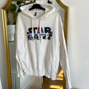 Vit Star Wars hoodie - Säljer en vit hoodie från H&Ms Star Wars kollektion. Hoodien har en justerbar huva med snören och långa ärmar. Perfekt för alla Star Wars-fans! 🌟