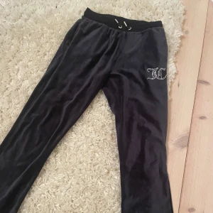 Svarta mjukisbyxor från Juicy Couture - Snygga svarta mjukisbyxor från Juicy Couture med glittrande logga på sidan. Byxorna har en bekväm resårmidja med snörning och två bakfickor. Säljer på grund av att jag inte använder dem längre . Sitter bra och är i lagom längd på mig( är 164cm). Barnstorlek men sitter som xs eller s. Kan sänka priset lite.